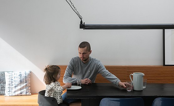 Filip en dochter Elle aan de zwart geschilderde eiken keukentafel.