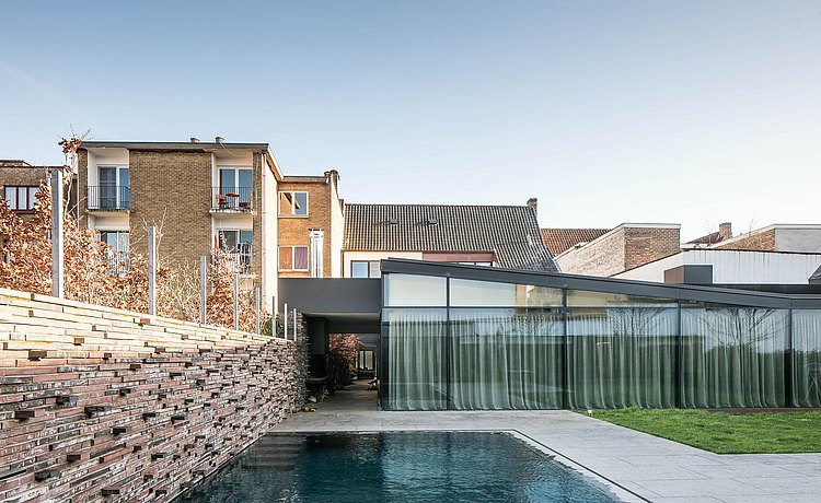 Aan de achterzijde heeft de gerenoveerde woning een schaduwtuin met een zwembad en poolhouse.