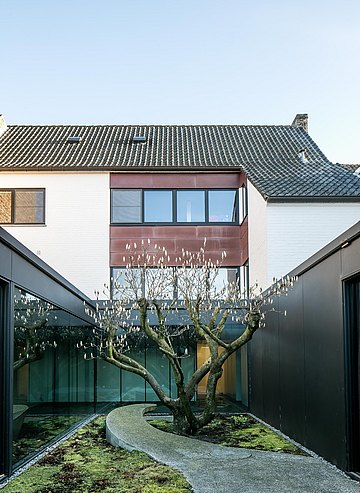 Un sentier en béton porphyre et un grand magnolia confèrent au patio intérieur un habillage expérimental.