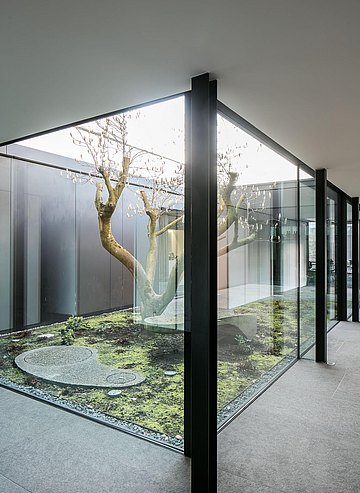 Un sentier en béton porphyre et un grand magnolia confèrent au patio intérieur un habillage expérimental.